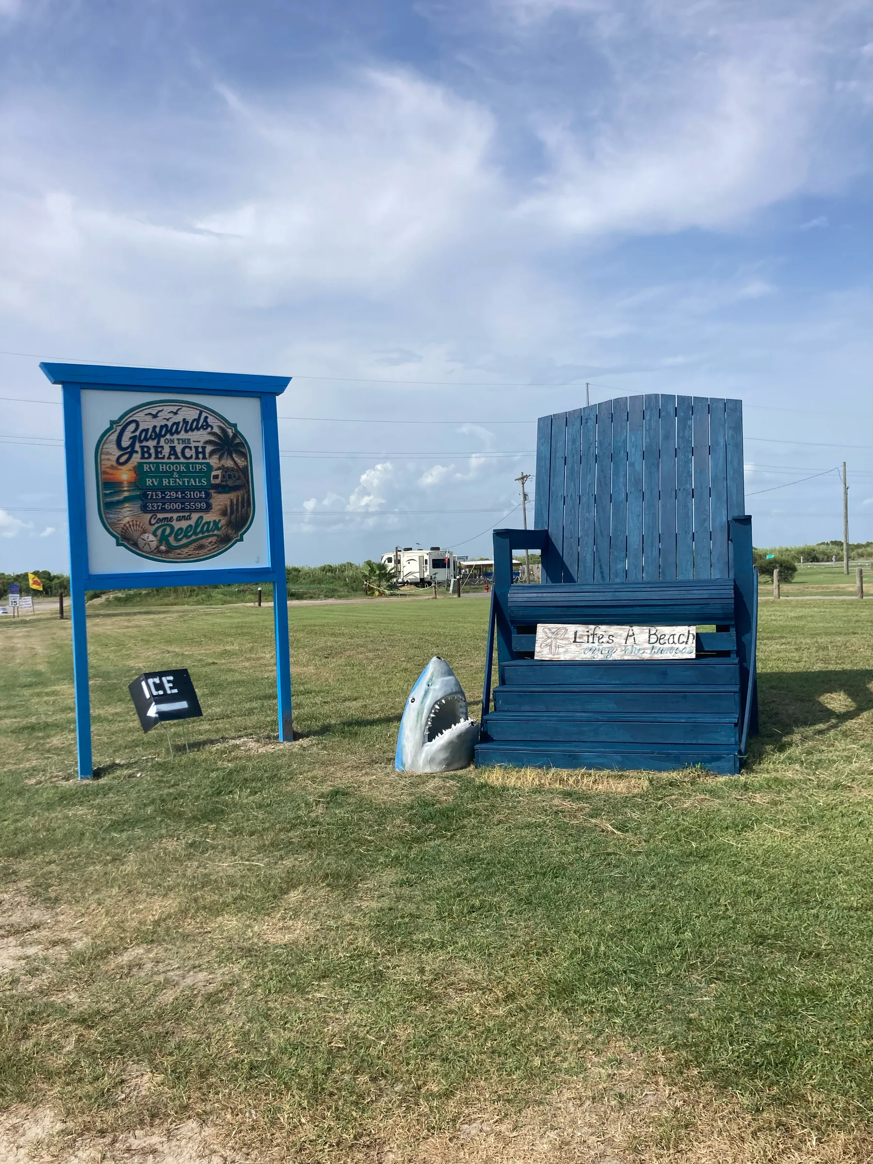 Giant blue beach chair and Gaspard's on the Beach sign under a bright Louisiana sky